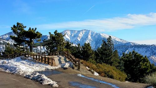 Scenic view of snowcapped mountains and wooden shelter against blue sky