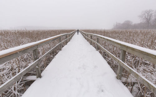 Snow covered boardwalk against sky