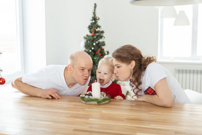 Happy family blowing christmas candle at home