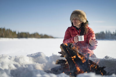 Woman holding mug near campfire