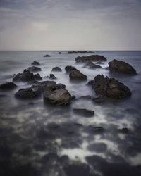 Rocks on sea shore against sky