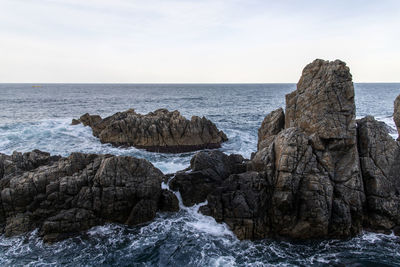 Rocks on sea shore against sky