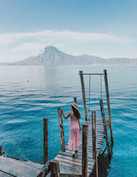 Wooden posts on pier by sea against sky