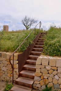 Staircase by footpath against sky