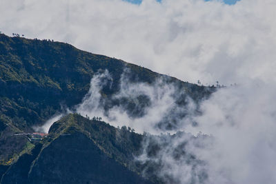 Low angle view of clouds over mountain against sky