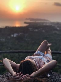 Woman lying down outdoors at sunset