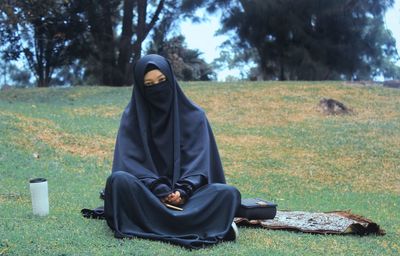 Portrait of woman in burka sitting on field