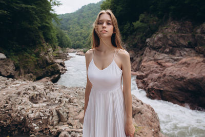 Portrait of young woman standing on rock