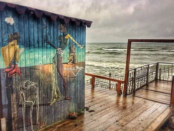 Pier on sea against cloudy sky