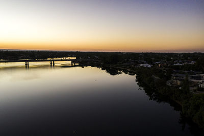 Scenic view of river by buildings against sky during sunset