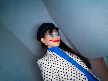 Portrait of woman with face paint standing against wall