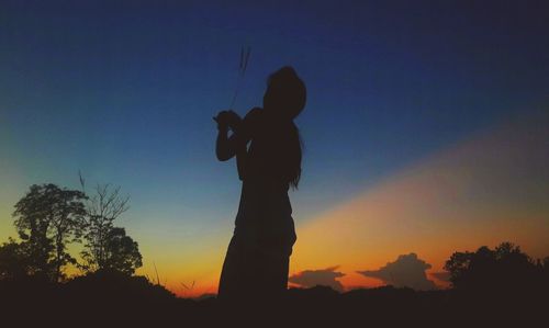 Low angle view of silhouette woman standing against sky during sunset