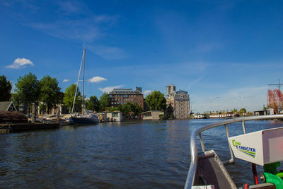 Boats moored in river with buildings in background