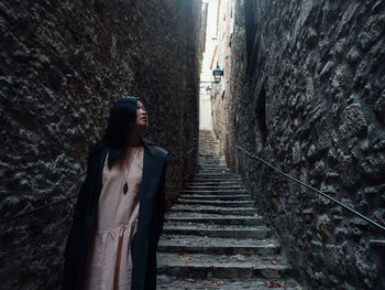 Woman standing on staircase by wall