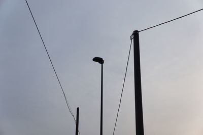 Low angle view of silhouette bird on street light against sky