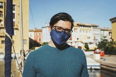 Portrait of young man standing against buildings