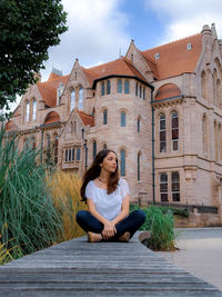 Full length of woman sitting against building