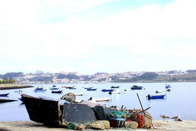 Boats moored at harbor against sky