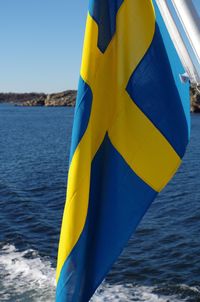 Close-up of yellow umbrella against blue sea