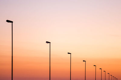 Low angle view of illuminated street lights against sky during sunset