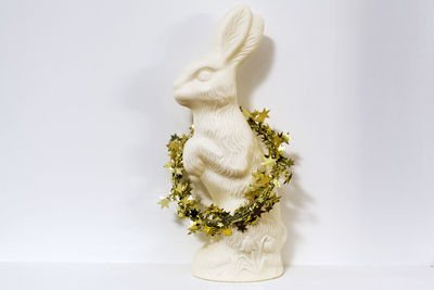 Close-up of figurine with wreath against white background