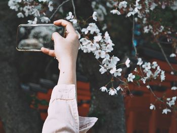 Midsection of person holding mobile phone outdoors