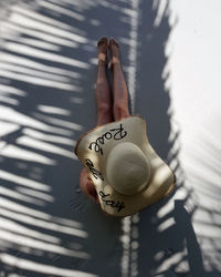 Directly above shot of woman wearing hat with text while sitting at beach