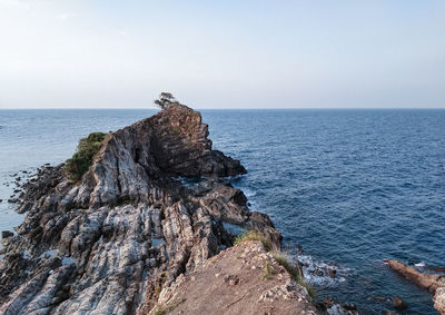 Rock formation in sea against clear sky