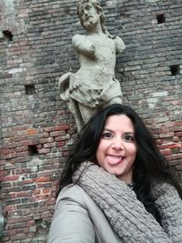 Portrait of a smiling young woman standing against brick wall