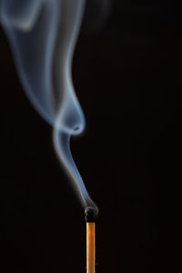 Close-up of emitting smoke against black background