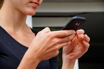 Midsection of young woman using mobile phone