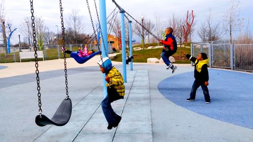 Children playing on swing in playground during winter