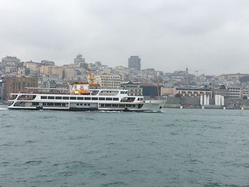 Boats sailing on sea against buildings in city