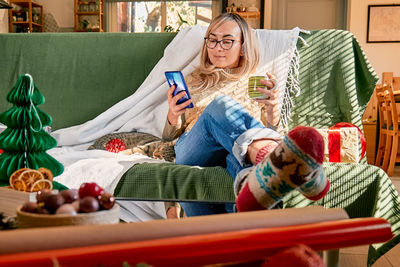 Happy blond woman buying holiday gifts using smartphone for searching promotion on black friday.