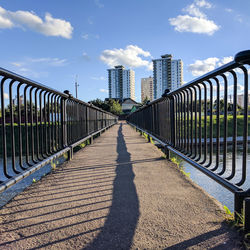 Footbridge in city against sky