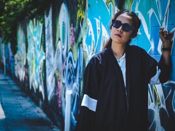 Woman standing by graffiti wall