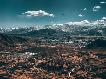 Aerial view of town and snowcapped mountains against blue sky