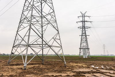 Low angle view of electricity pylon on field