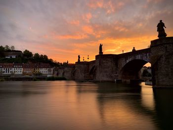 Arch bridge over river during sunset