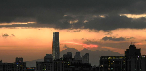 View of cityscape against dramatic sky during sunset