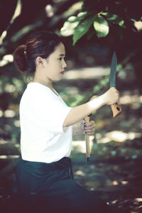 Side view of woman holding knife practicing martial arts outdoors