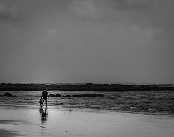 Silhouette woman standing on beach against sky