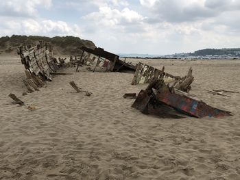 Driftwood on beach by sea against sky