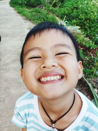 Close-up portrait of smiling boy on footpath at park