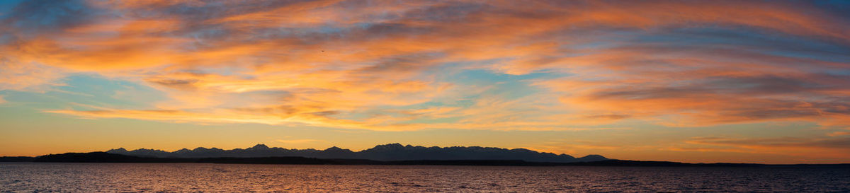 Scenic view of calm sea against cloudy sky during sunset