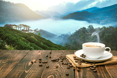 Coffee cup on table against mountains