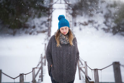 Woman standing on footbridge during snowfall