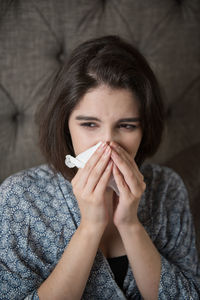 Woman with tissue paper sneezing at home