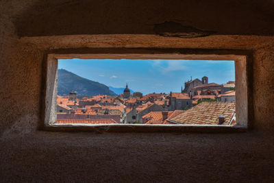 Buildings against sky seen through window