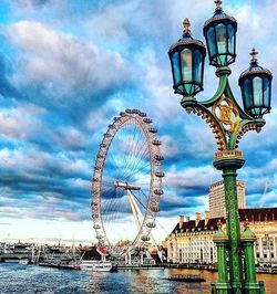 Low angle view of ferris wheel against cloudy sky